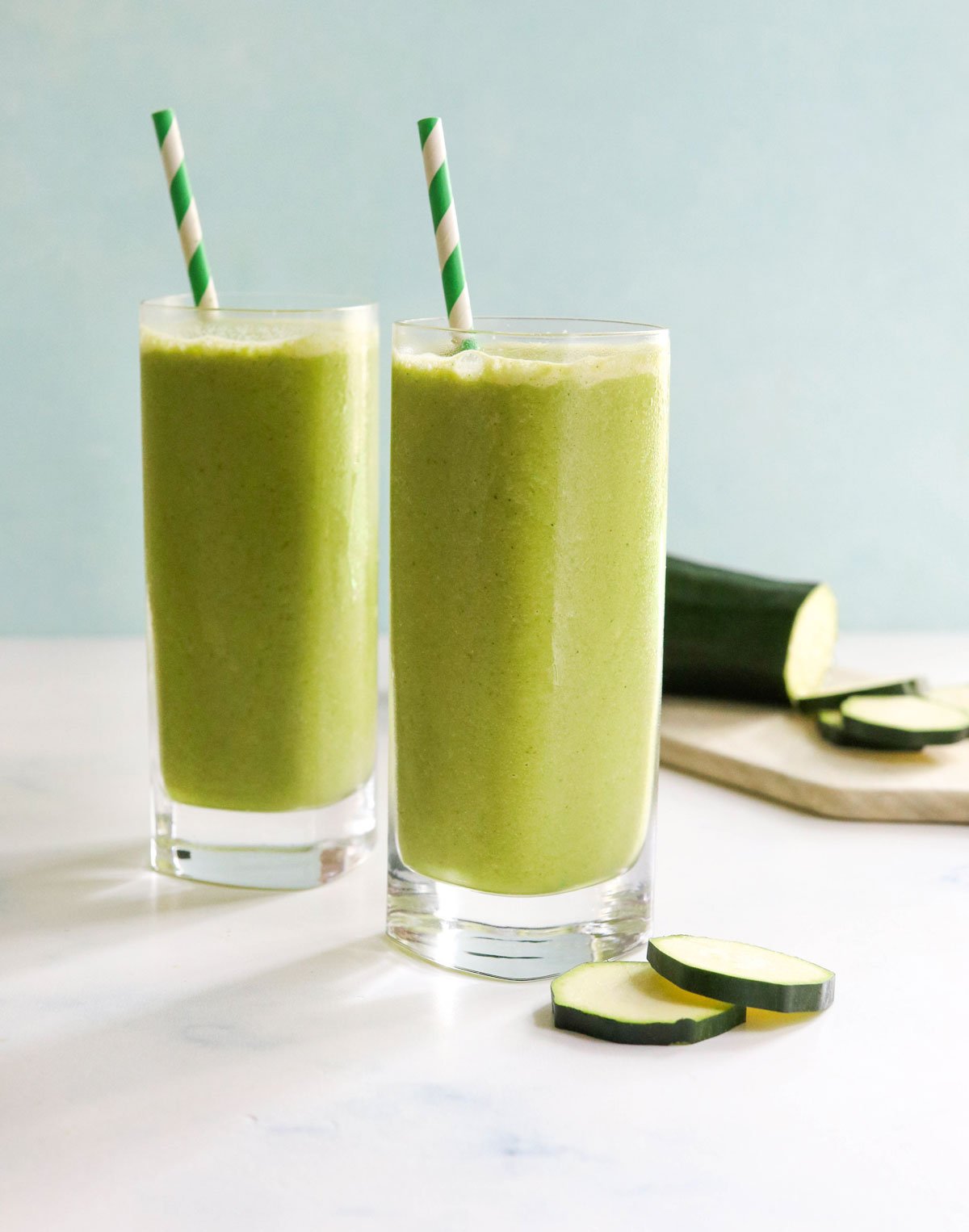 zucchini smoothie in two glasses with straws