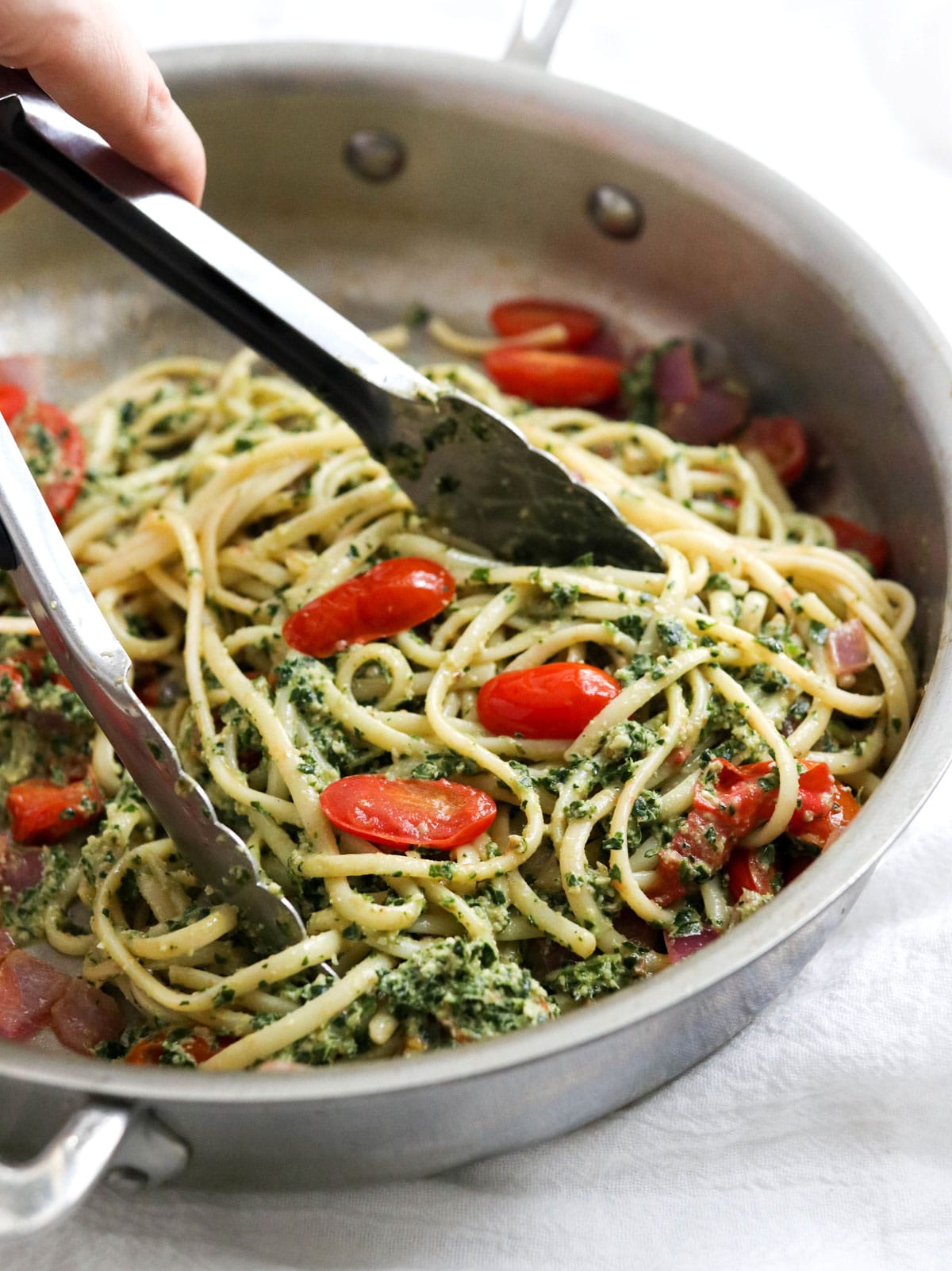 kale pesto tossed with noodles in pan