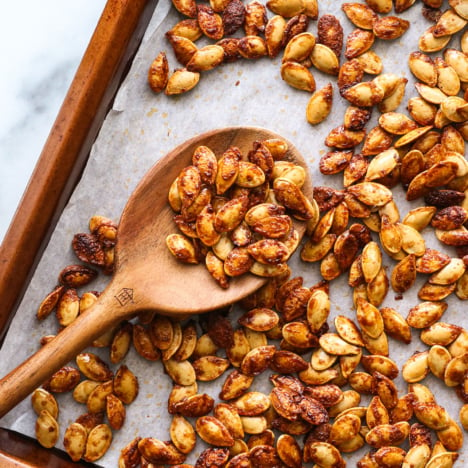 pumpkin seeds roasted on a lined pan with a wooden spoon.