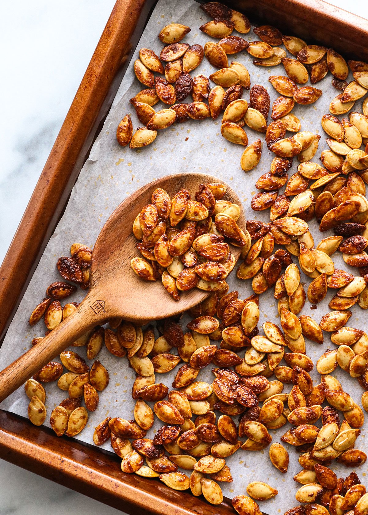 pumpkin seeds roasted on a lined pan with a wooden spoon.