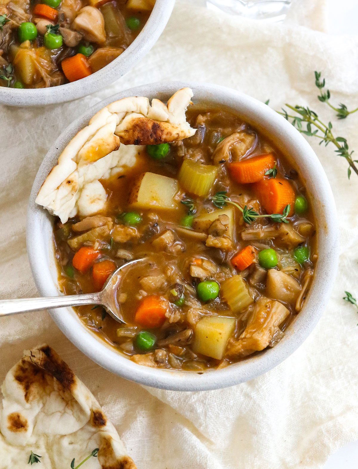 vegetable stew with a spoon and bread inside the bowl.