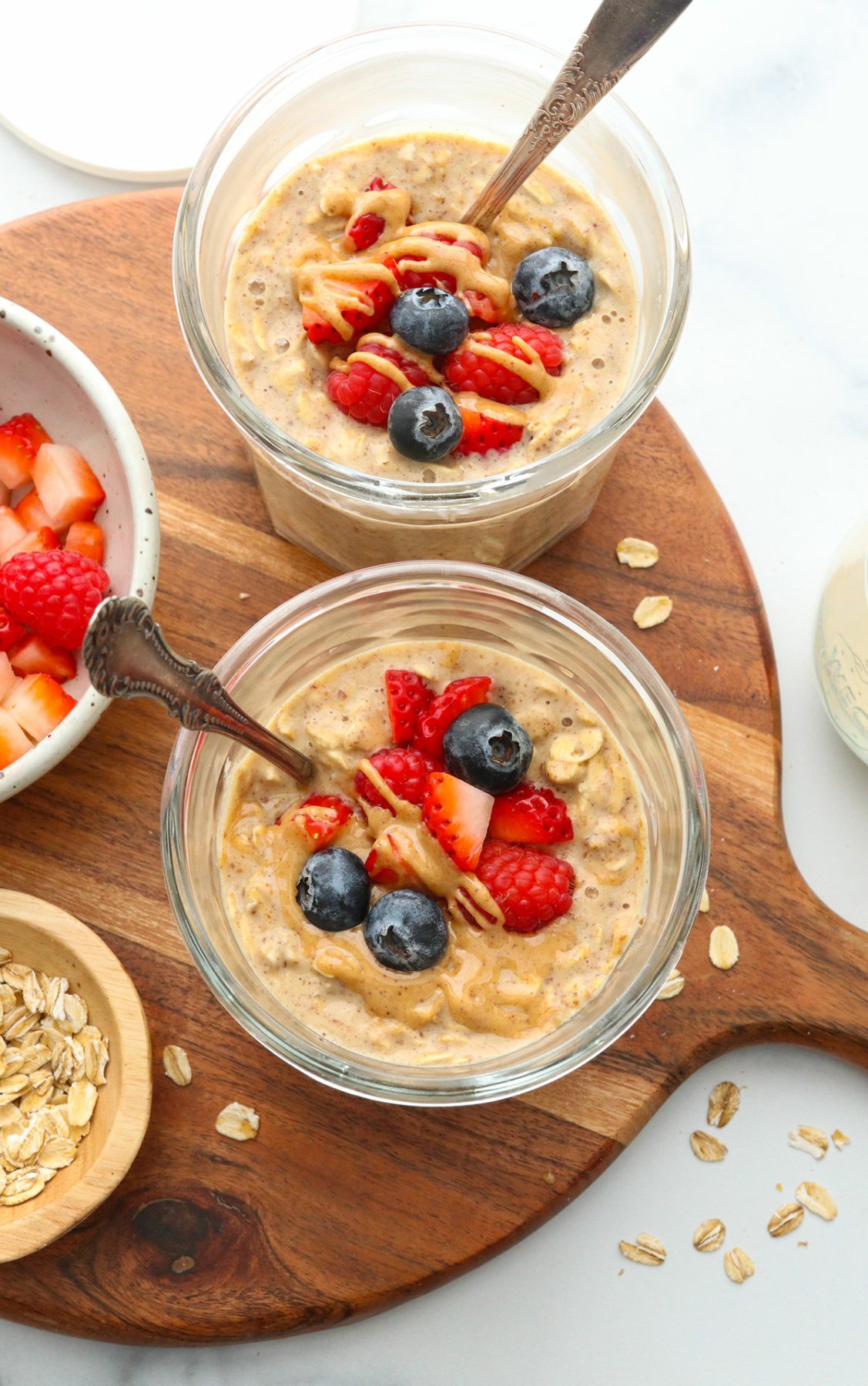 peanut butter overnight oats in two glass jars topped with berries.
