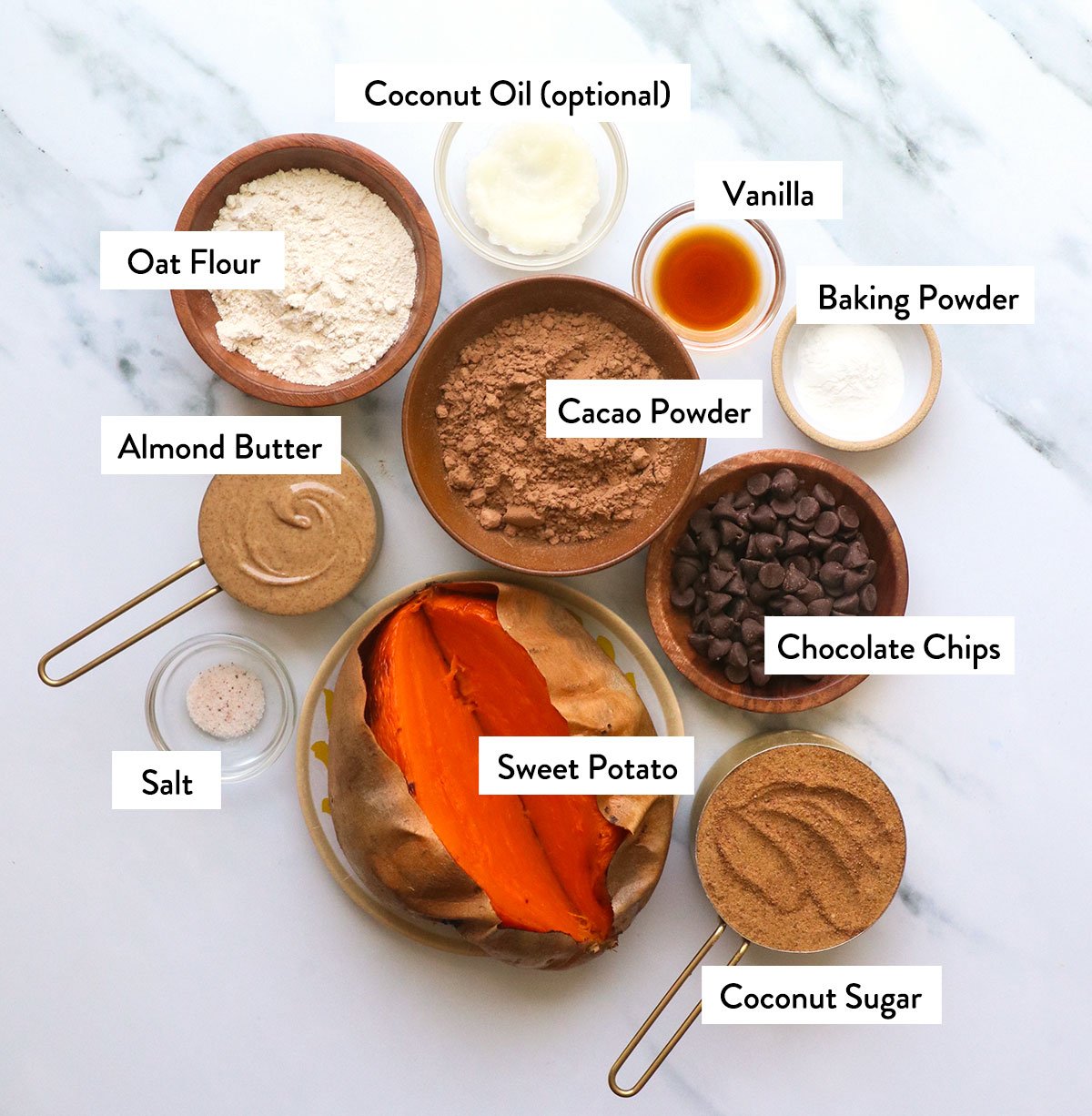 sweet potato, cacao powder, oat flour, almond butter, and sugar labeled on a white surface. 