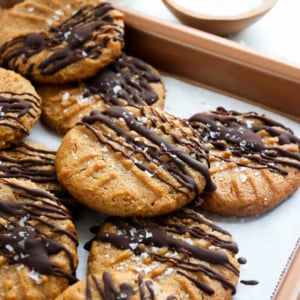 peanut butter cookies drizzled with dark chocolate on baking sheet