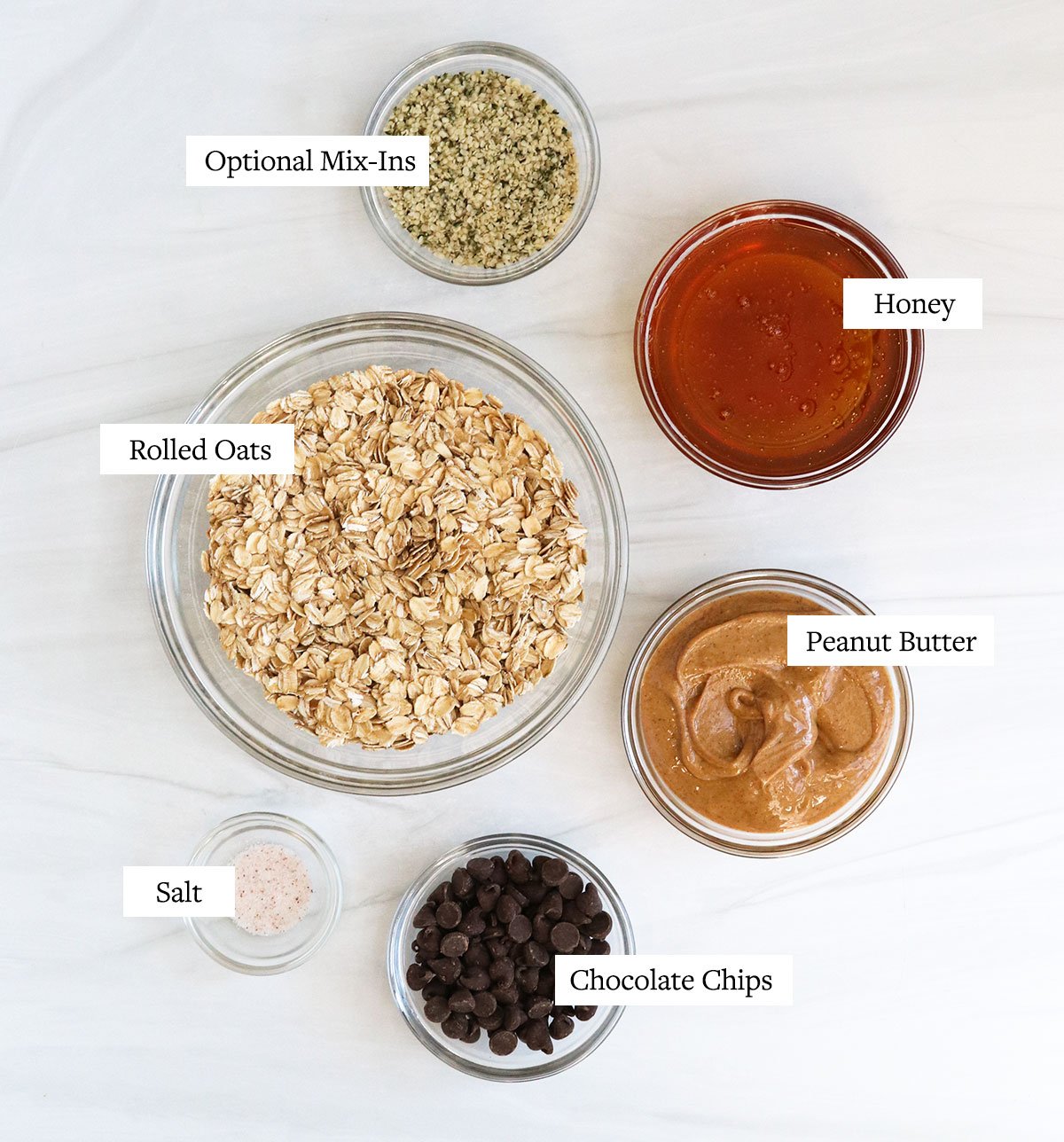 granola bar ingredients labeled in glass bowls.