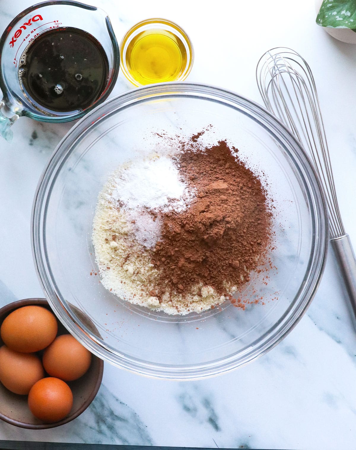 large glass bowl filled with cacao powder, almond flour, and baking powder.