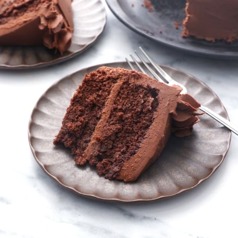 slice of chocolate almond flour cake on a plate with frosting.