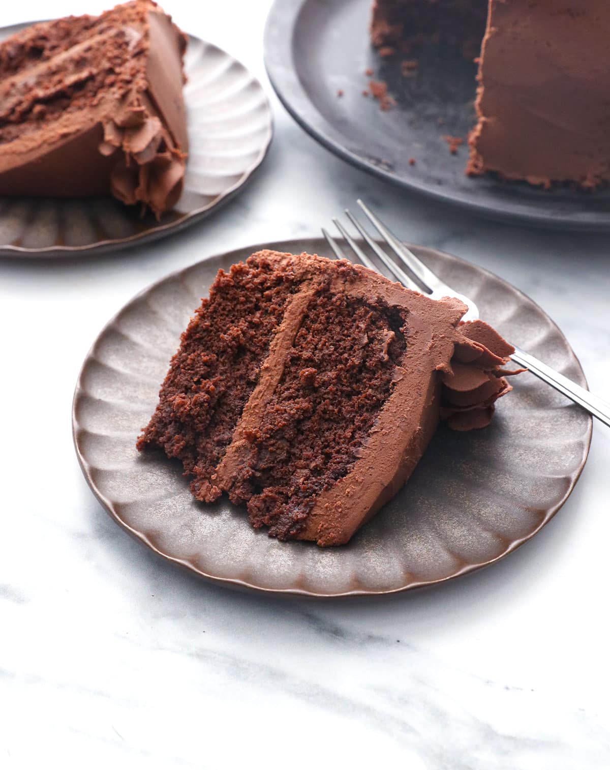 slice of chocolate almond flour cake on a plate with frosting.
