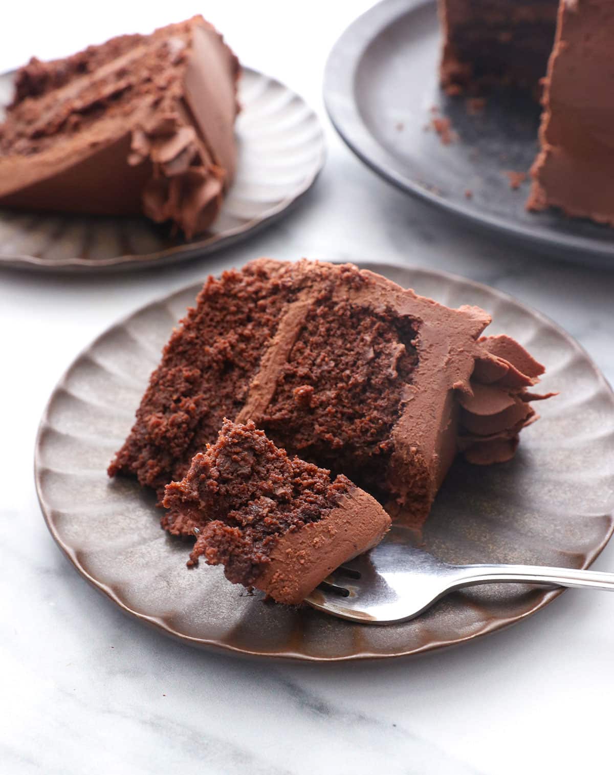 slice of chocolate almond flour cake on a dark plate with a fork.