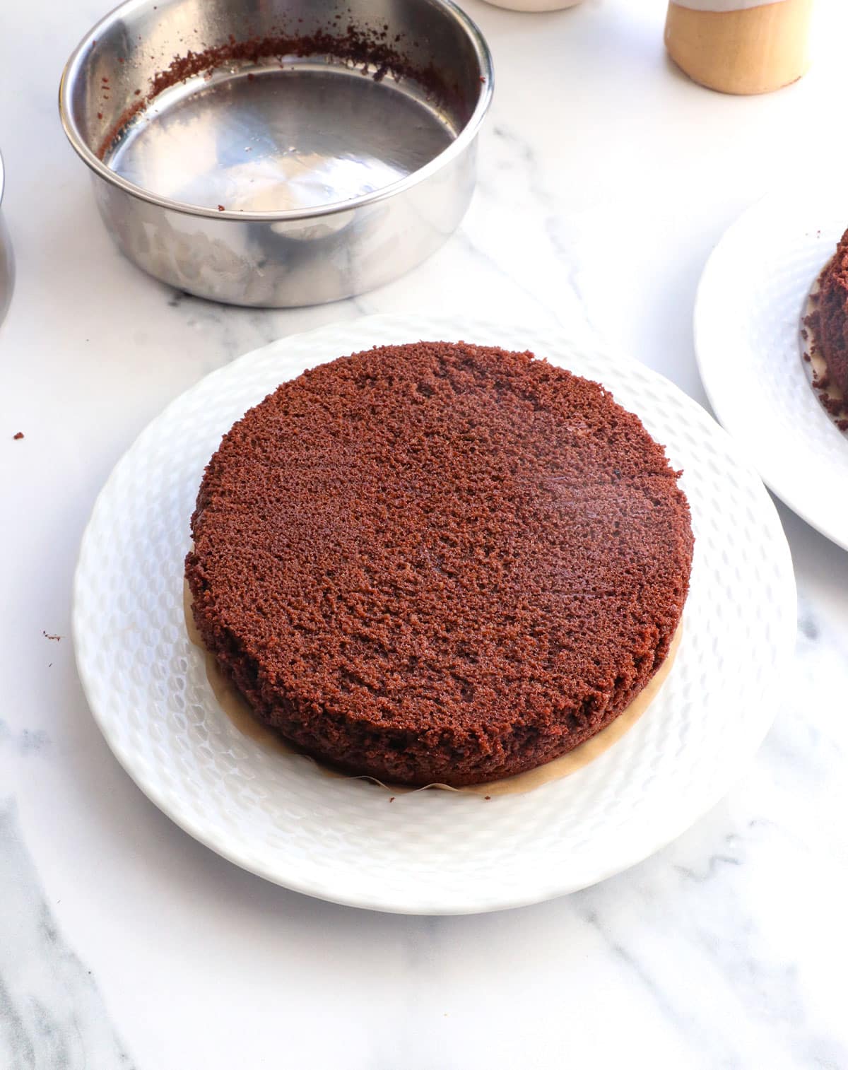 cake flipped onto a white plate to finish cooling.