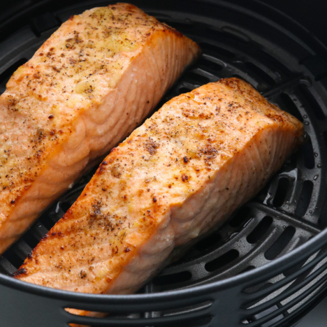 two salmon fillets cooked in an air fryer basket.
