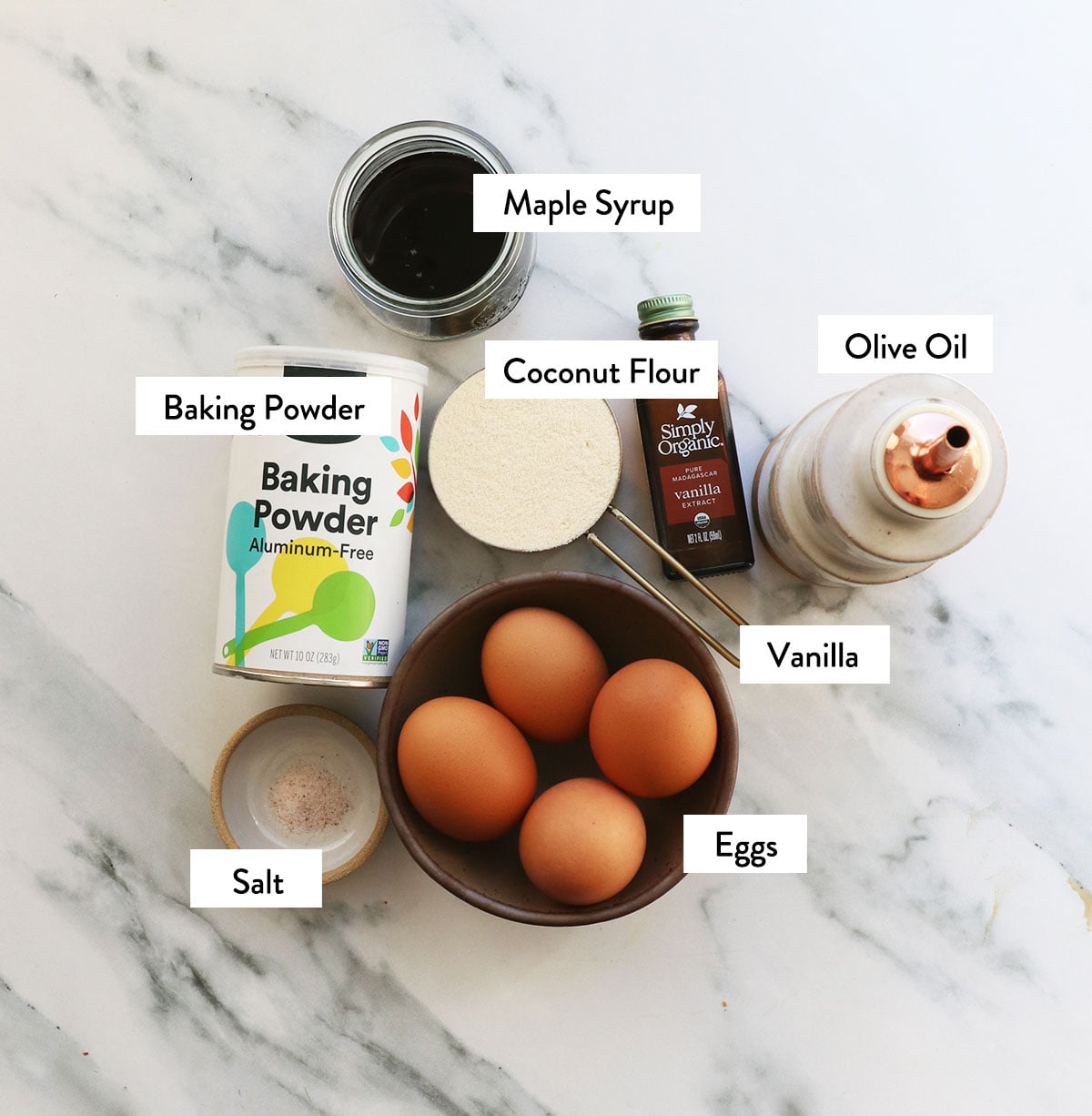 coconut flour, eggs, oil, baking powder, and maple syrup labeled in bowls.