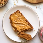 oat flour banana bread slice topped with peanut butter on a plate.