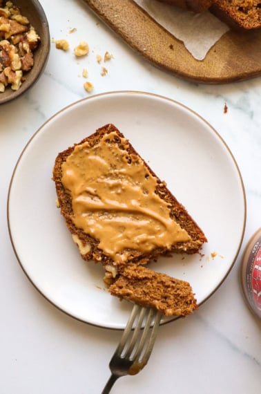 oat flour banana bread slice topped with peanut butter on a plate.
