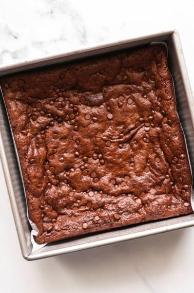 paleo brownies baked in a metal square pan with parchment paper.