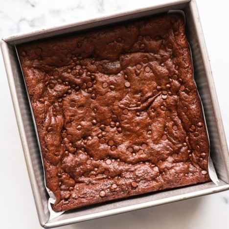 paleo brownies baked in a metal square pan with parchment paper.