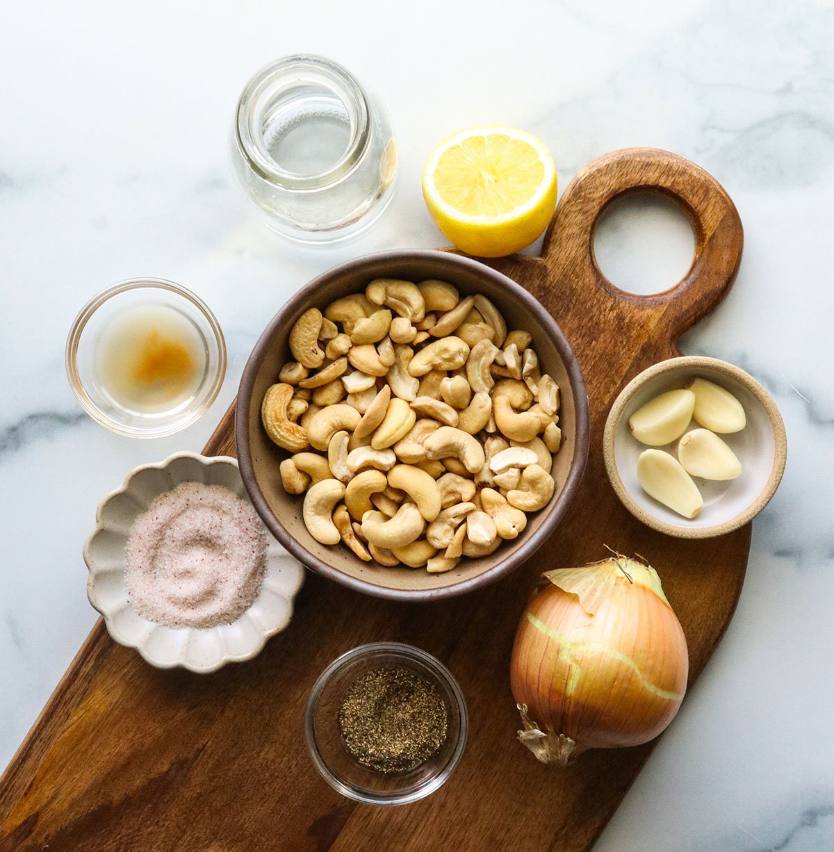 cashews, onion, and lemon juice on a cutting board to make alfredo.