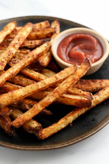 baked french fries on black plate with ketchup
