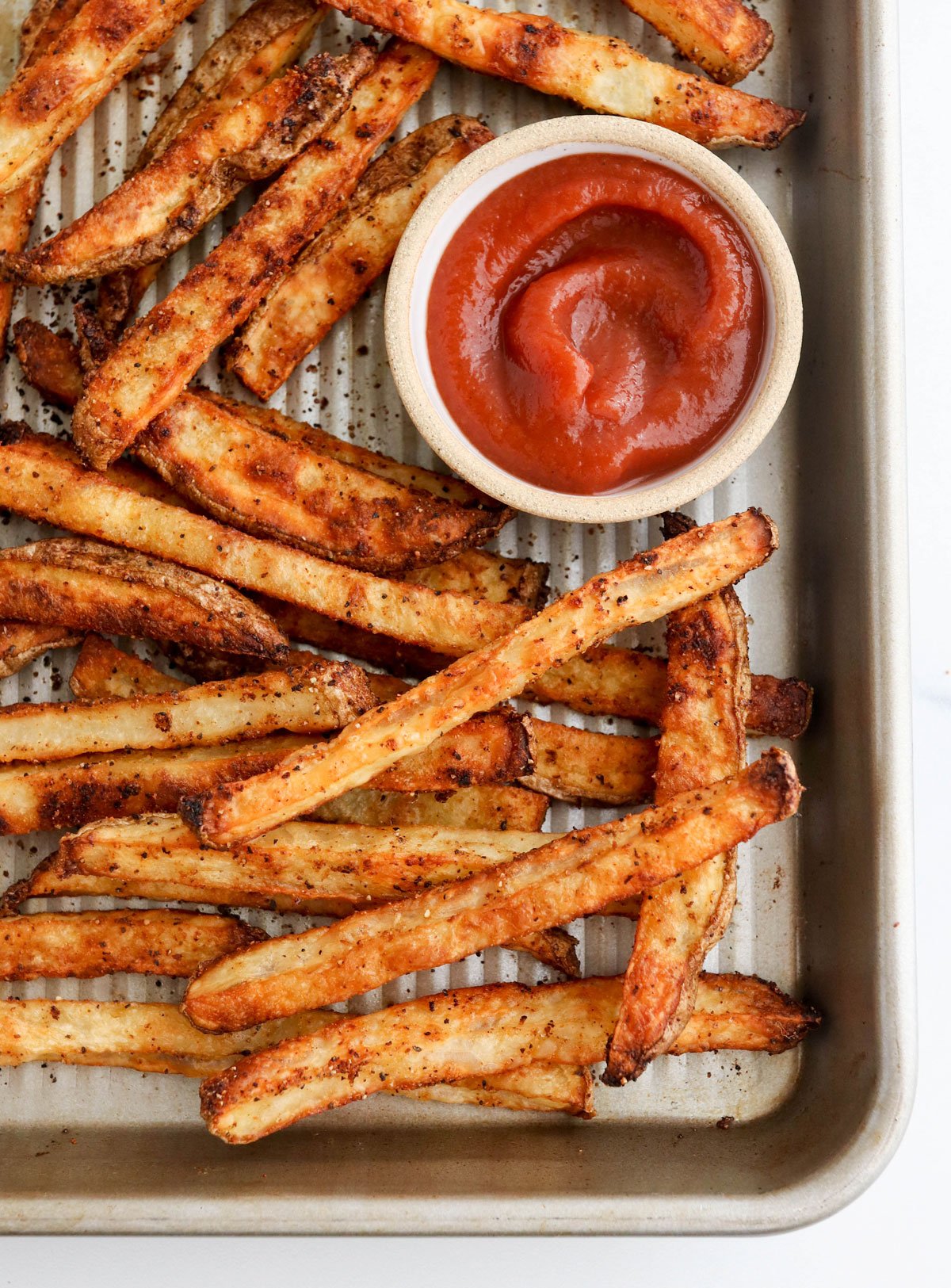 baked french fries on sheet pan with ketchup