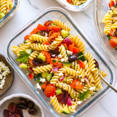 greek pasta salad served in glass meal prep containers.