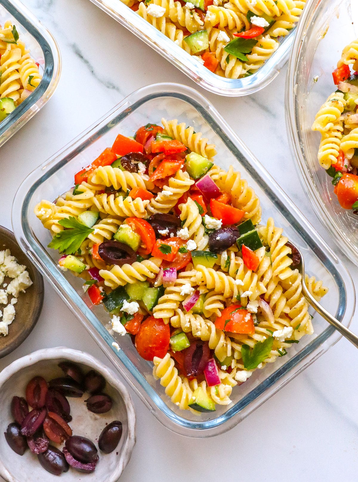 greek pasta salad served in glass meal prep containers.