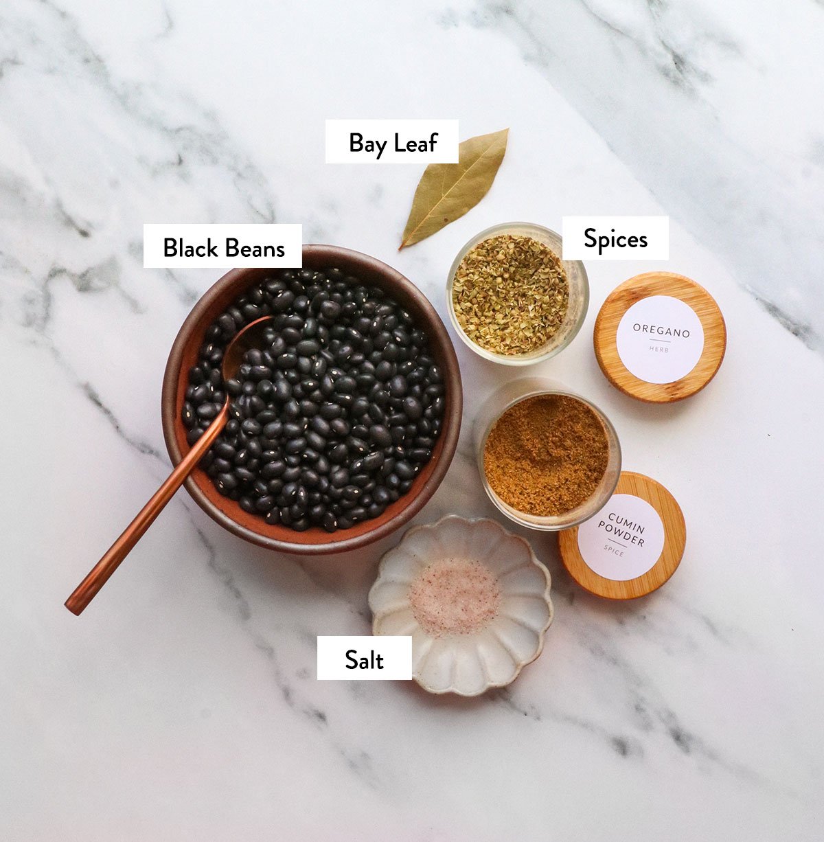 Dried beans and spices mark in container on white surface.