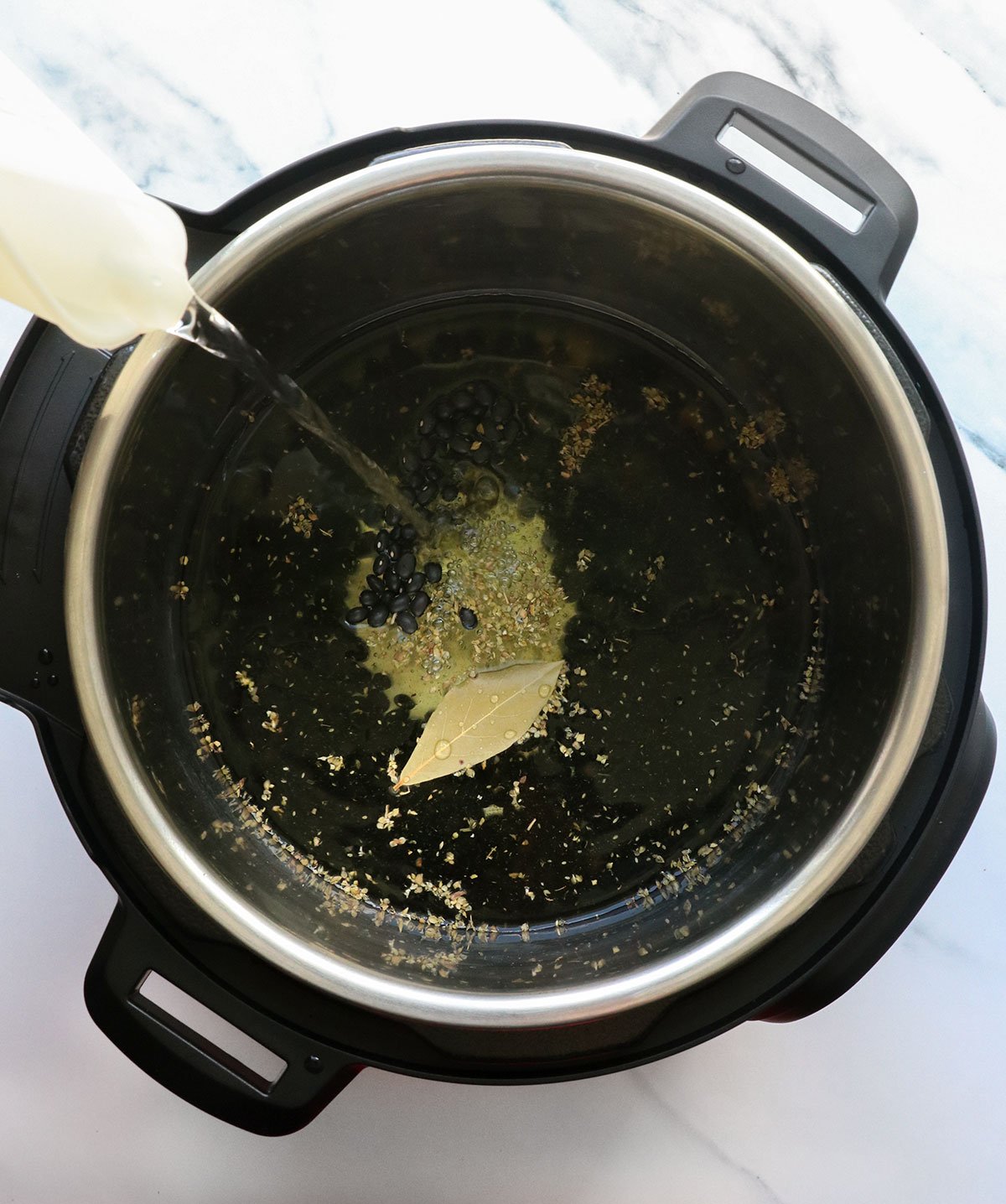 Water and spices are added to the dry beans in a pressure cooker.