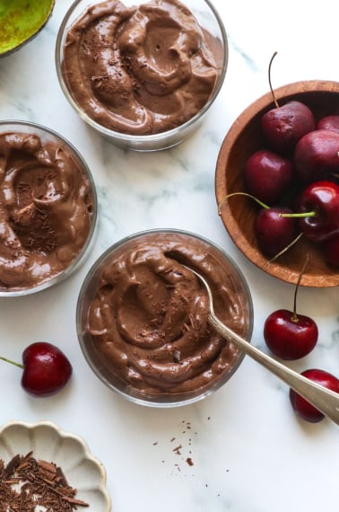 cherry chocolate avocado pudding served in 3 glass dishes.