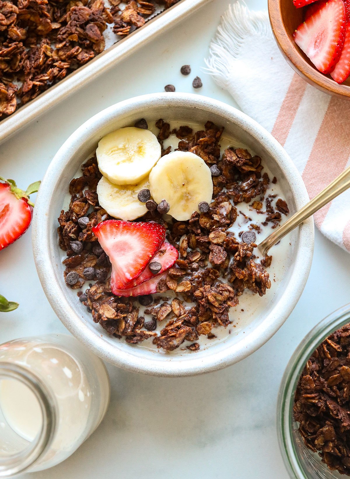 A bowl of chocolate granola topped with fresh fruit and mini chocolate chips. 