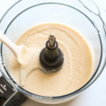 Coconut butter in a food processor with a spatula.