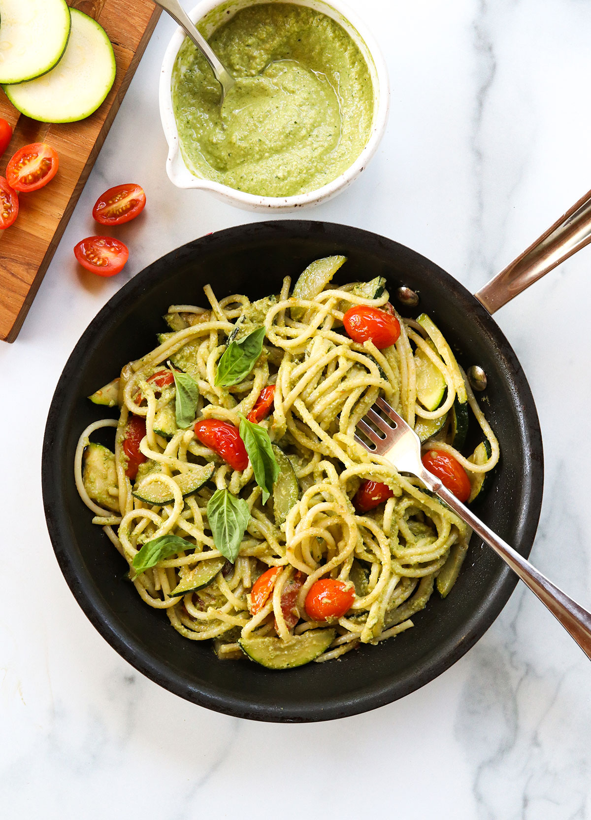 pasta tossed with zucchini, cherry tomatoes, and pesto in skillet.