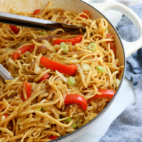 singapore noodles in pan with tongs