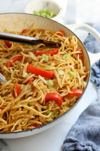 singapore noodles in pan with tongs