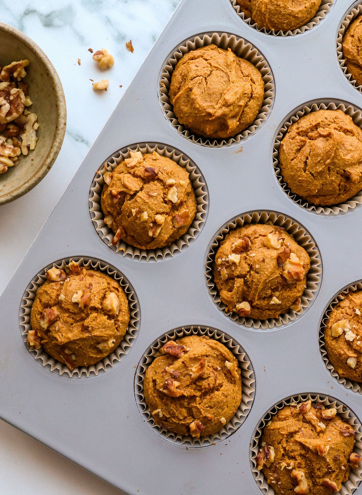 finished muffins in the pan with walnuts on top.