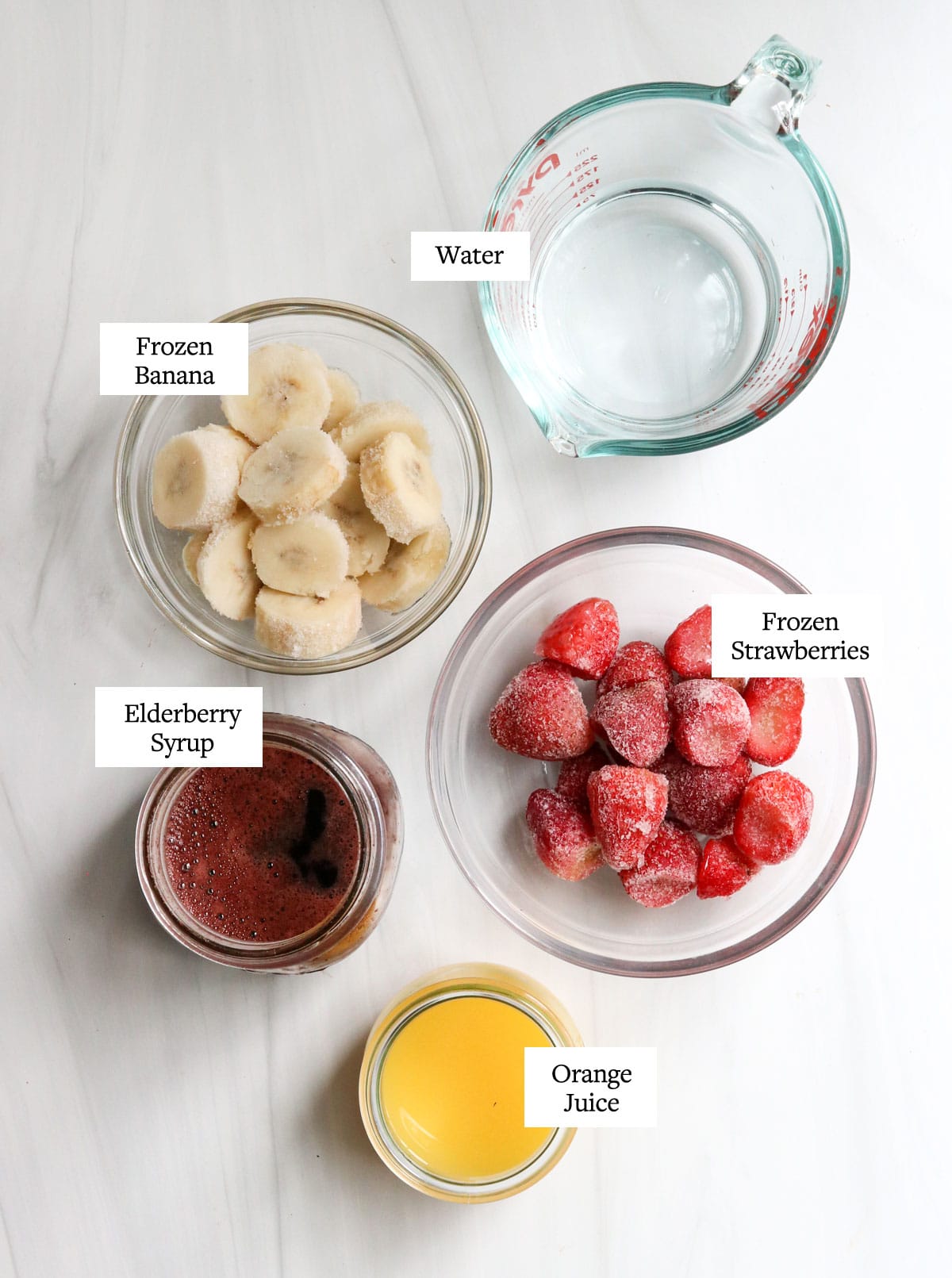 elderberry smoothie ingredients in glass bowls on white surface