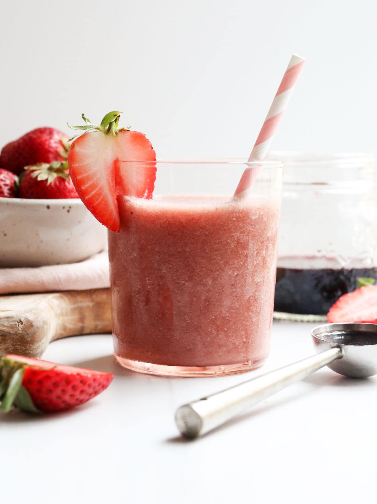 elderberry smoothie in glass with pink straw and strawberry