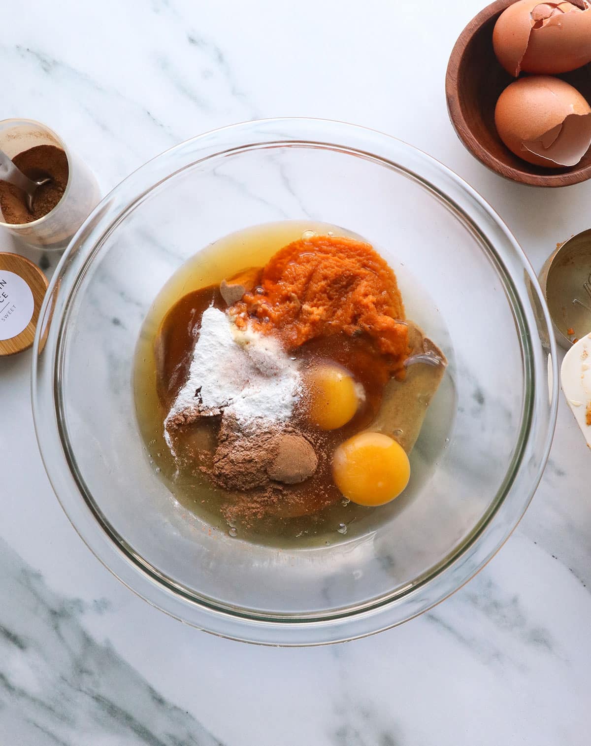 canned pumpkin, eggs, almond butter, and honey added to a glass mixing bowl. 
