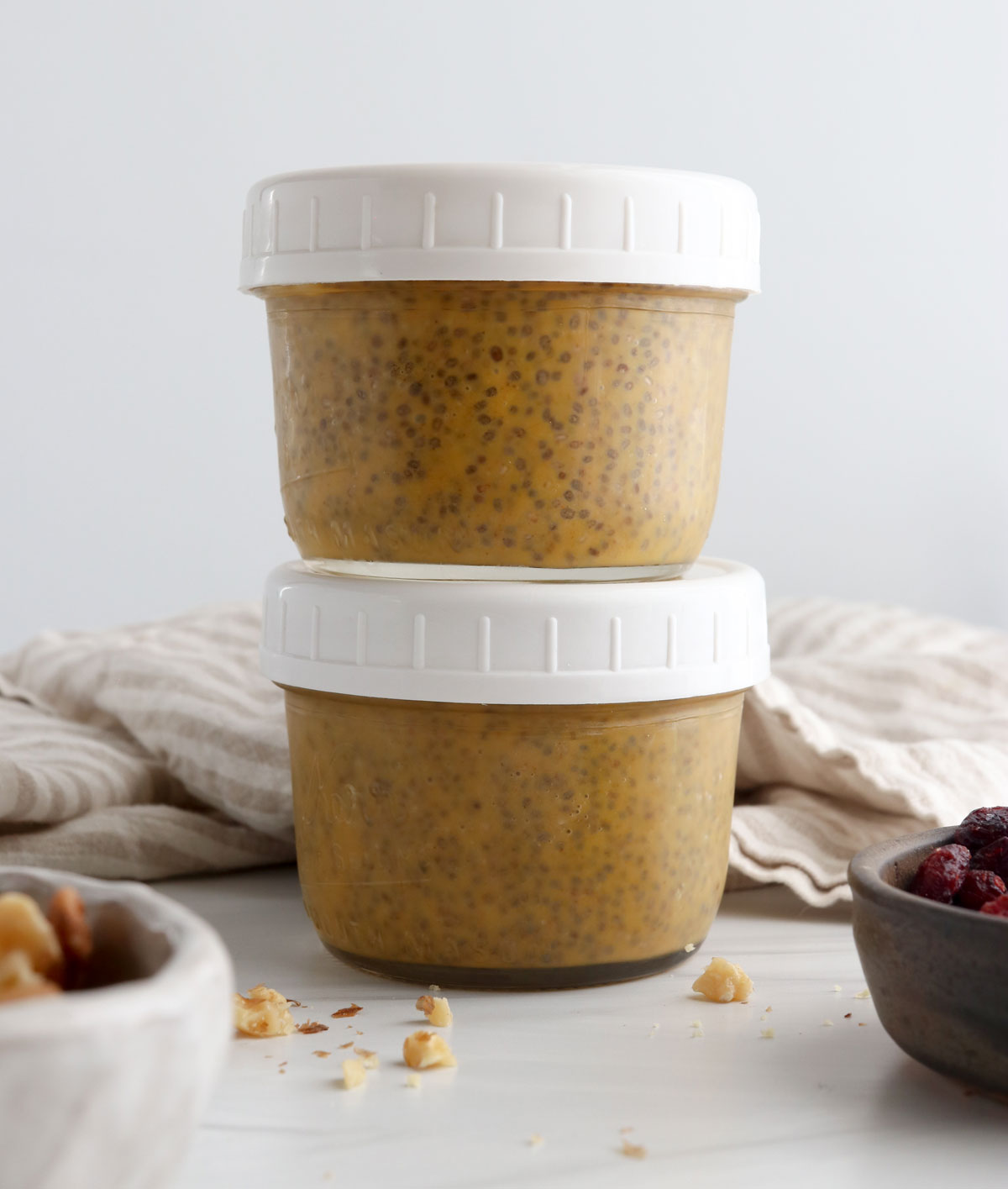 two jars of pumpkin chia pudding stacked with lids