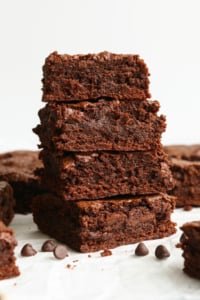 oat flour brownies stacked in front of a white wall.