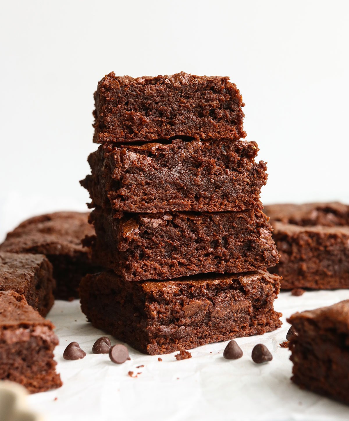 oat flour brownies stacked in front of a white wall.