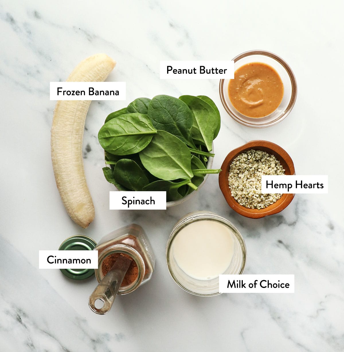 bowl of spinach, frozen banana, peanut butter, cinnamon, milk, and hemp hearts labeled in bowls.