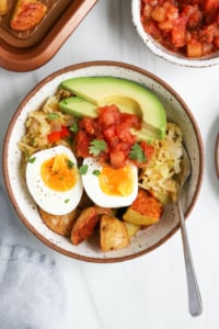 breakfast bowl topped with salsa and avocado with a serving fork