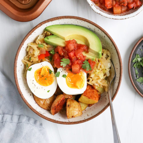 breakfast bowl topped with salsa and avocado with a serving fork