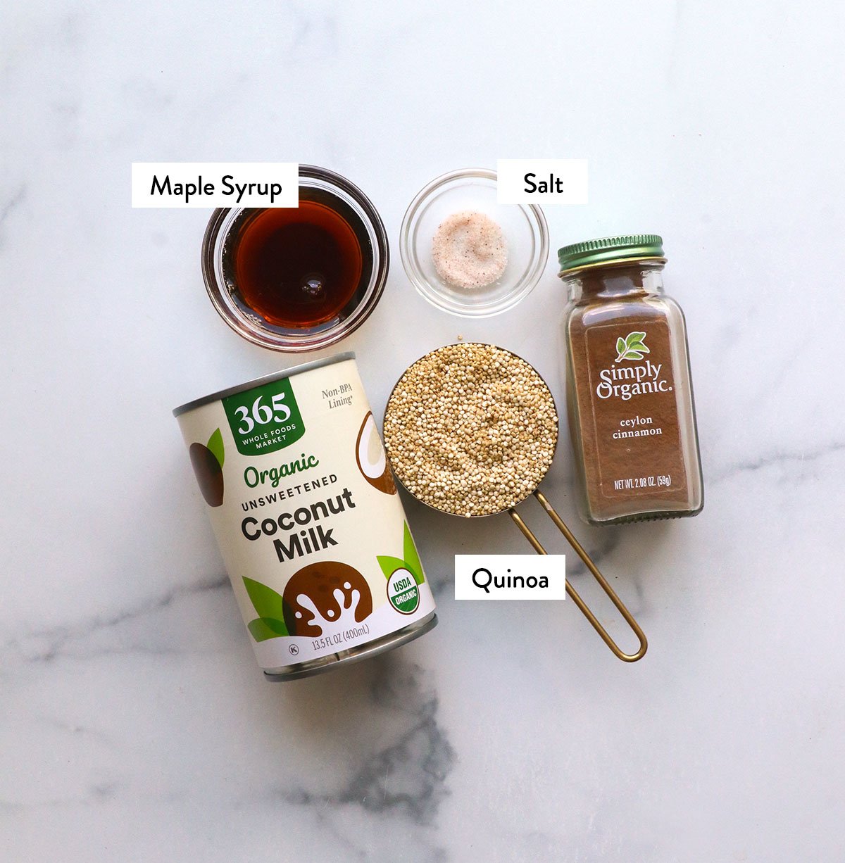 quinoa, coconut milk, cinnamon and maple syrup labeled on a white surface.