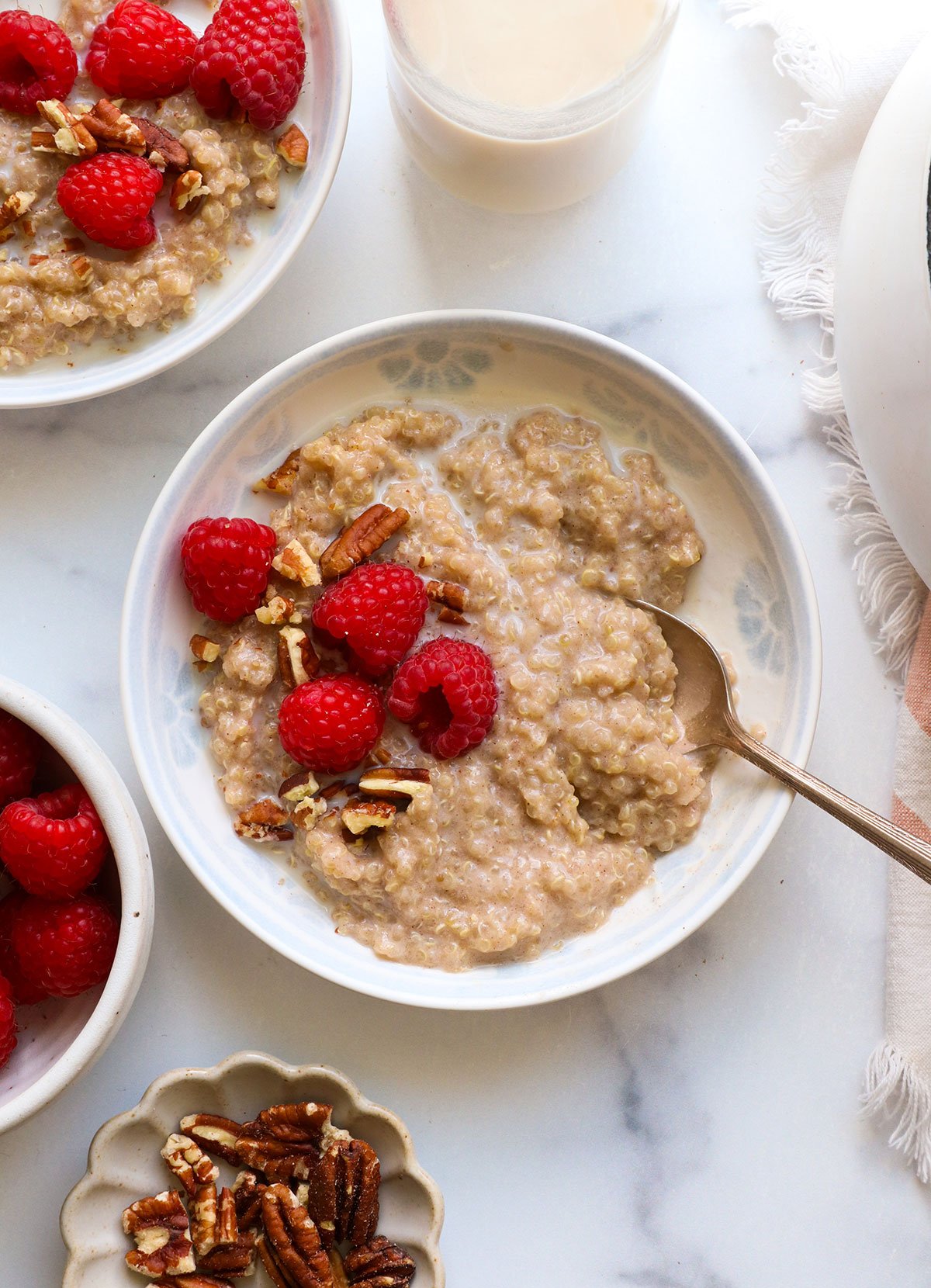 quinoa porridge in a white bowl topped with raspberries.