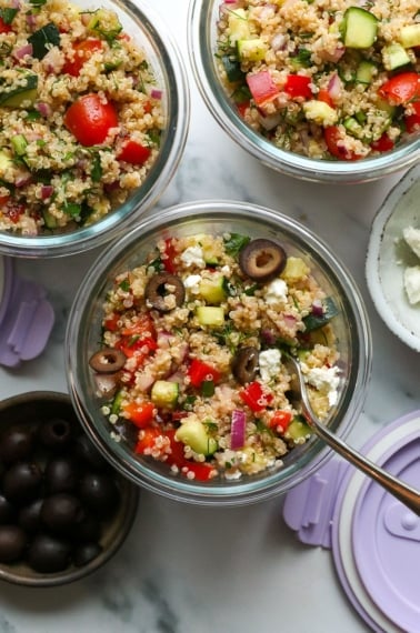 quinoa salad served in meal prep glass jars with black olives and feta cheese.
