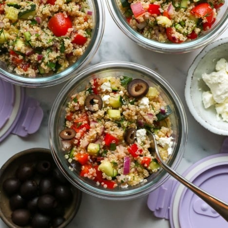 quinoa salad served in meal prep glass jars with black olives and feta cheese.