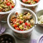 quinoa salad in individual meal prep jars with black olives and feta on top.