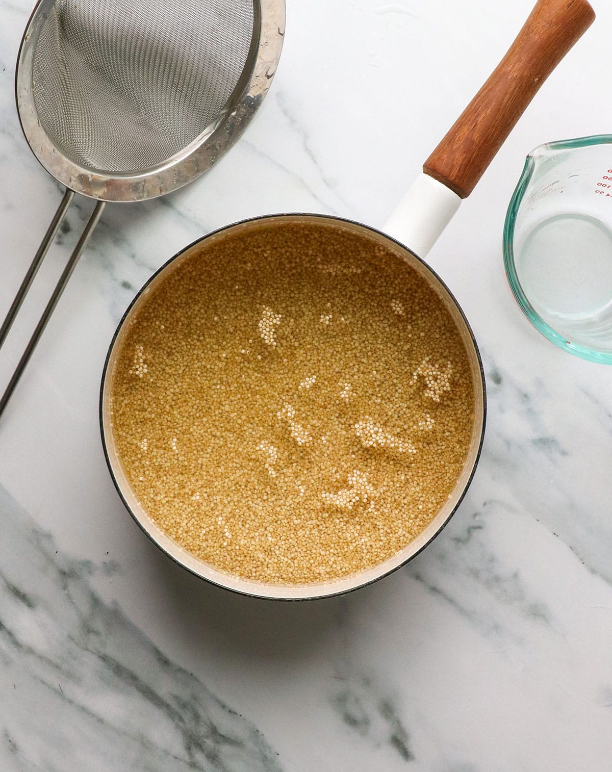 water added to quinoa in a white saucepan.