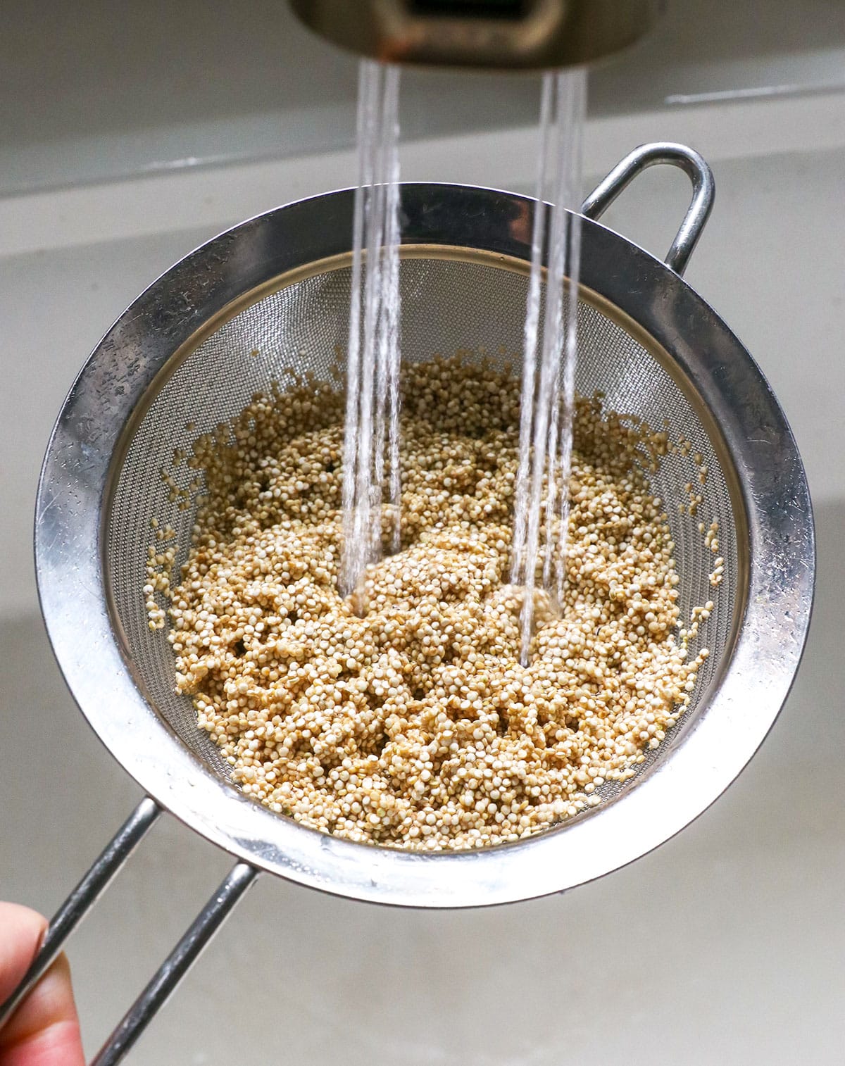 rinsing quinoa under running water in a fine mesh sieve.